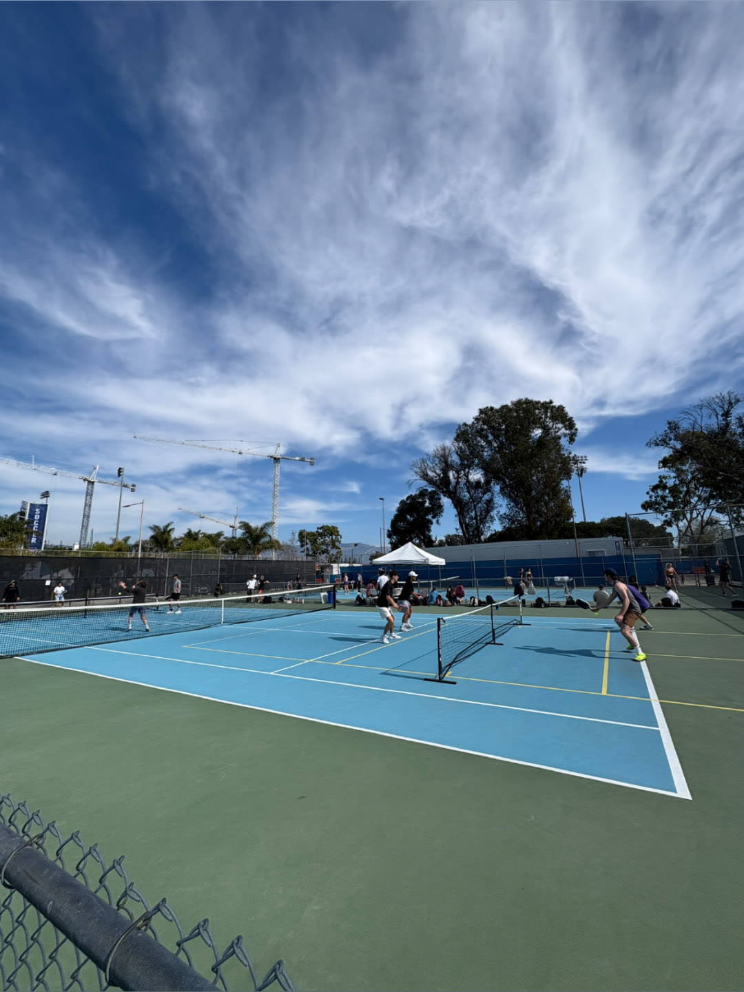 Players mid-rally across multiple pickleball courts at an outdoor event